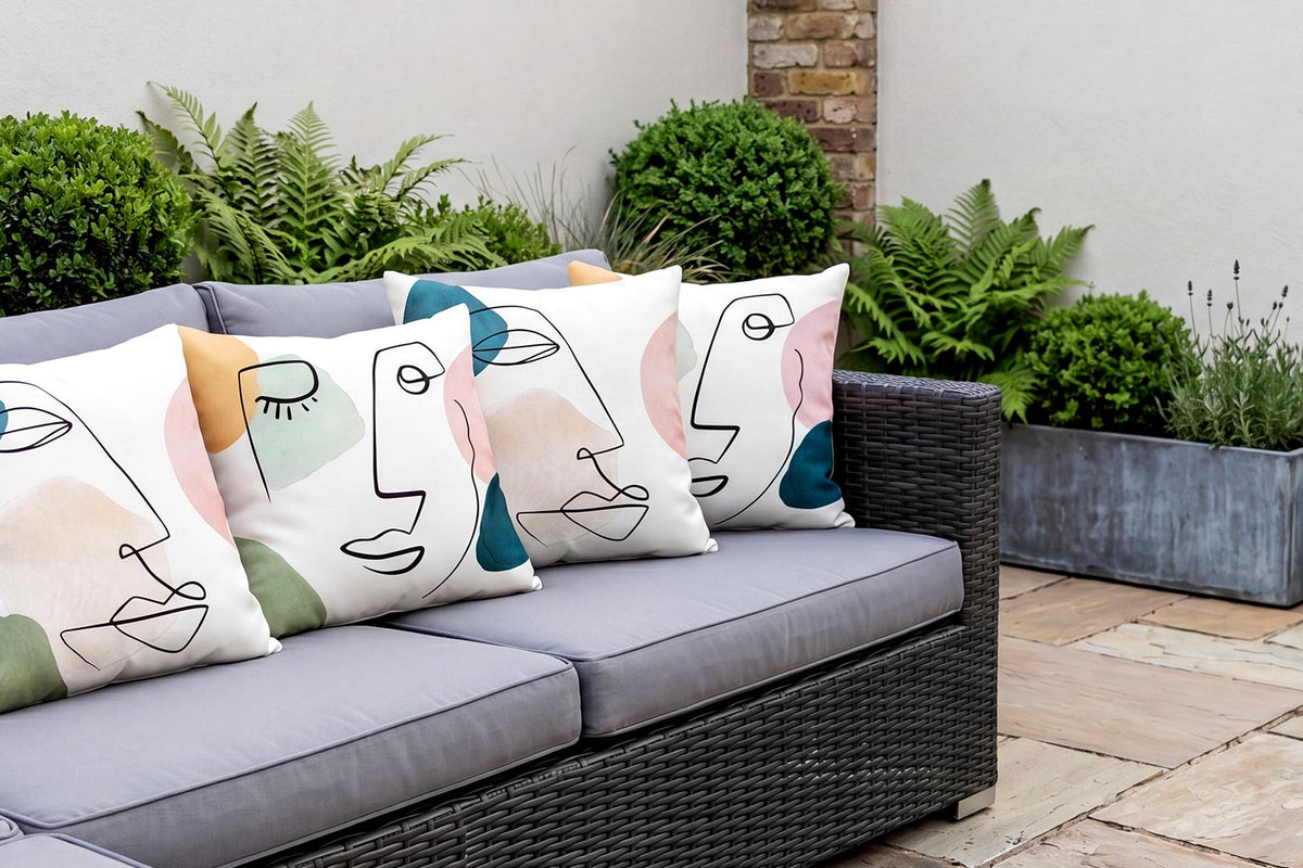 Abstract face-design outdoor garden cushions on a grey rattan sofa
