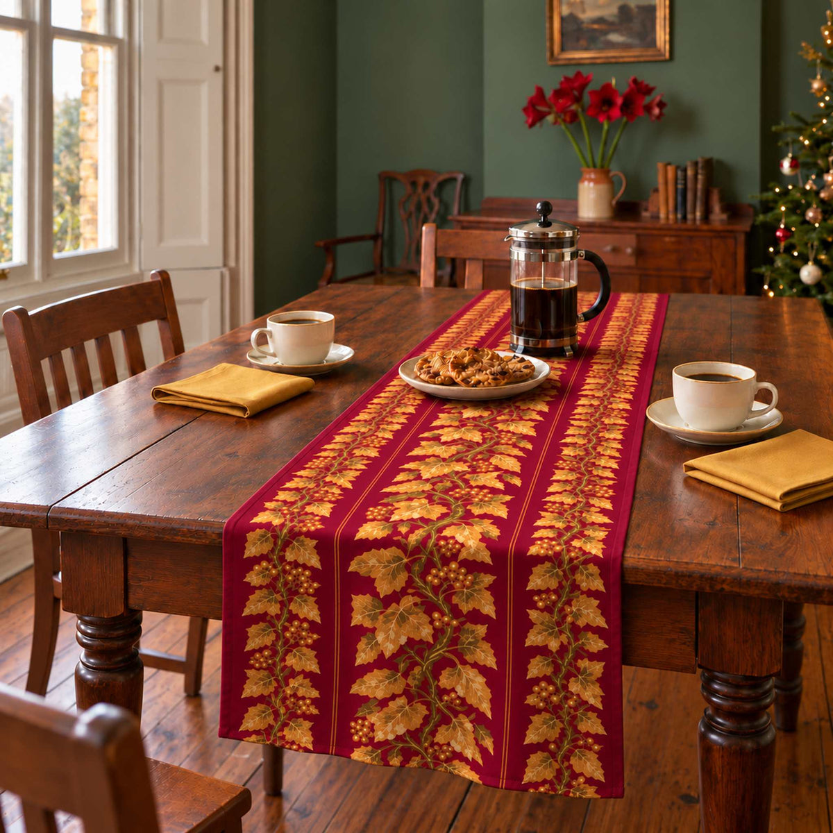 Gilded Ivy Christmas table runner in Burgundy and gold, styled on a wooden table with a softly draped end in a daylight Christmas room.