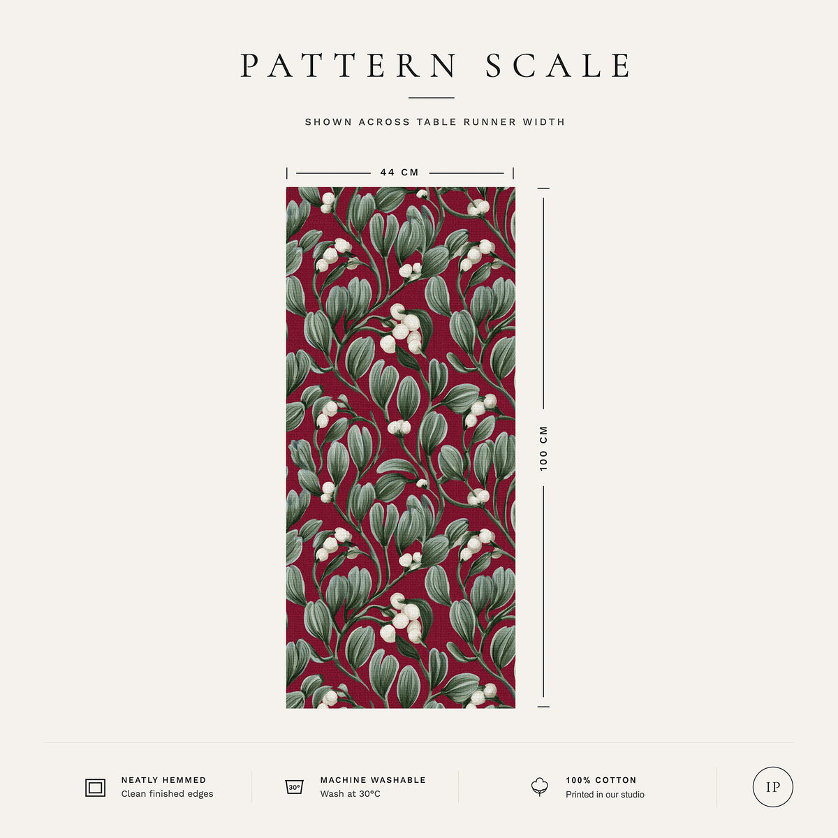 Pattern scale of the Mistletoe Christmas table runner in burgundy across its 44 cm width, with care notes