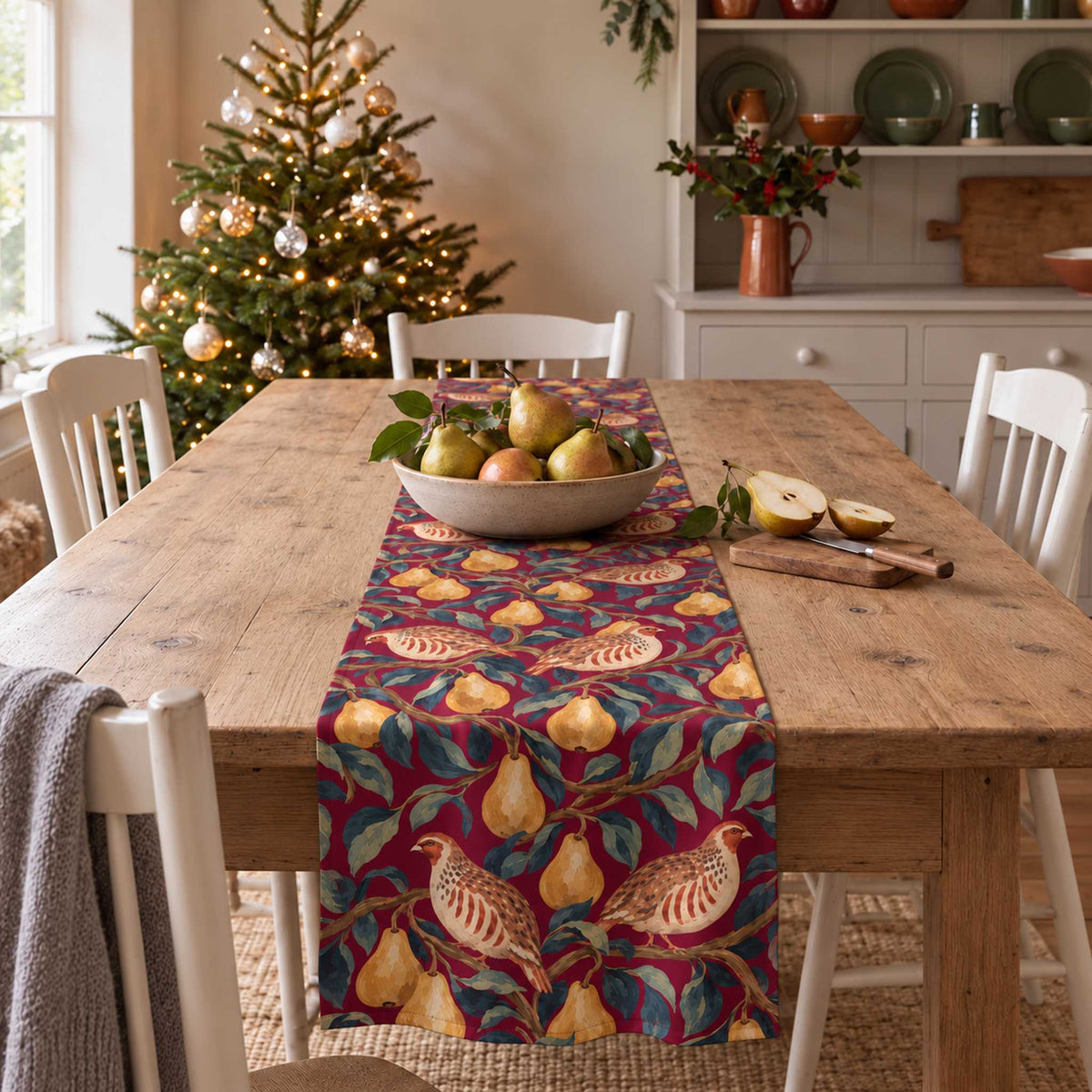 Partridge and Pear Christmas table runner in Burgundy, styled on a wooden table with a softly draped end in a daylight Christmas room.