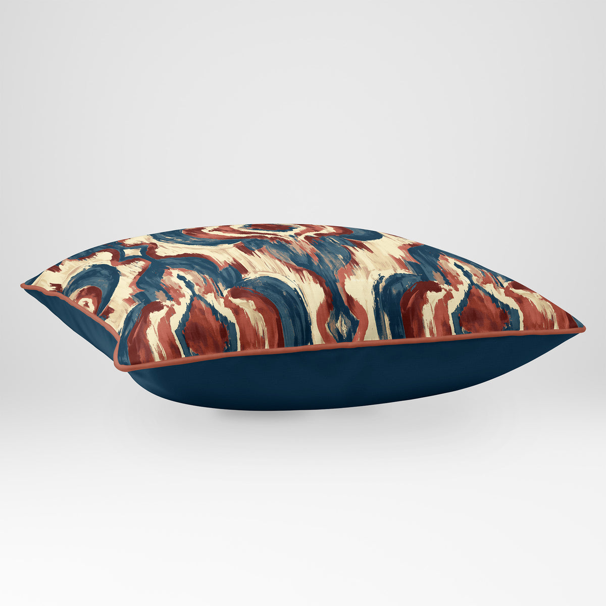 Angled view showing the front and Deep Teal plain reverse of a Court Medallion rectangular cushion in Teal & Persimmon, finished with Persimmon piping.