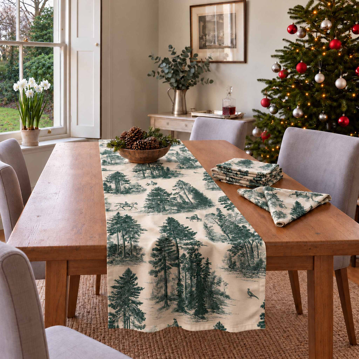 Fir Forest Toile Christmas table runner in Green on ivory, styled on a wooden table with a softly draped end in a daylight Christmas room.