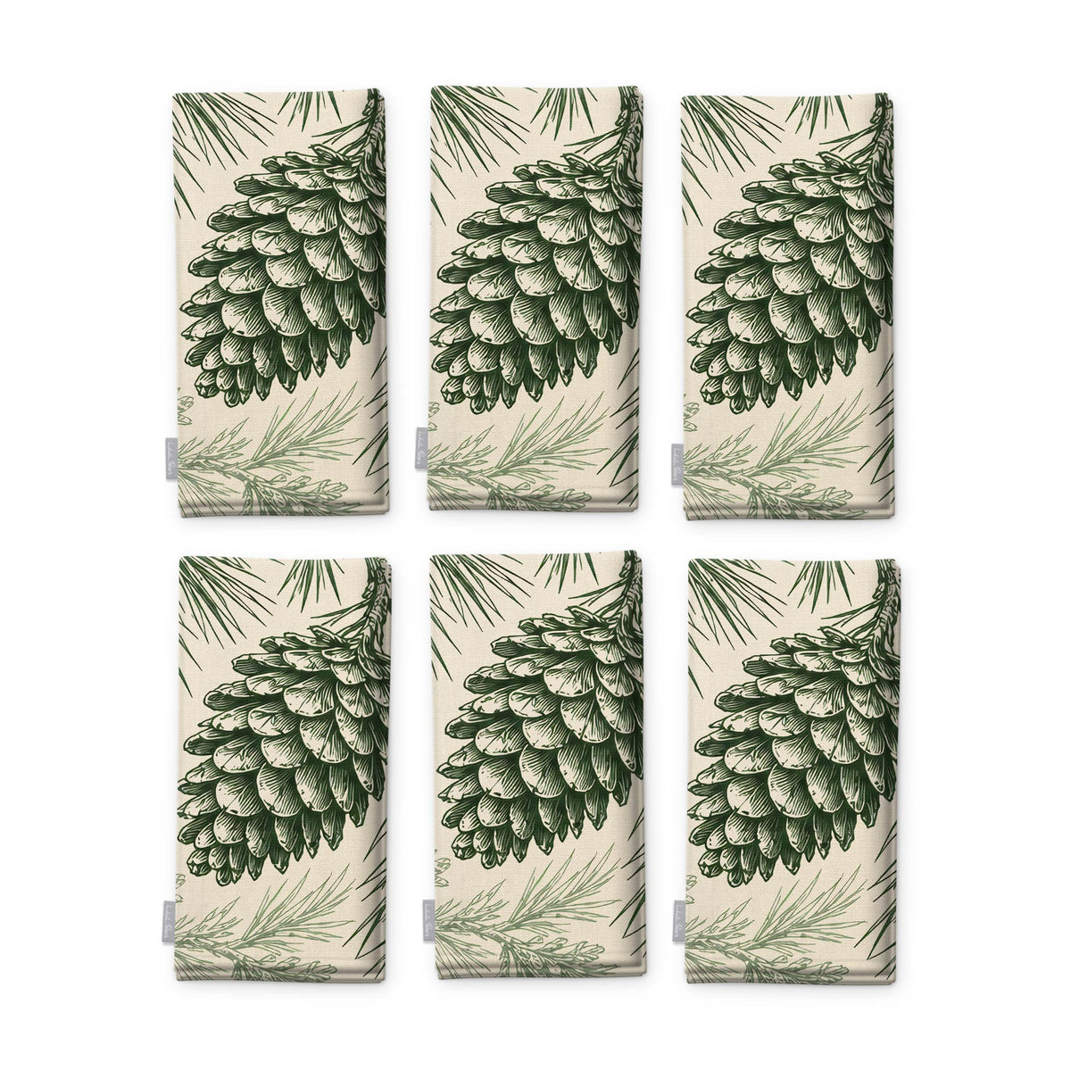 Pine Bough Christmas napkins in green on ivory, set of six, folded on white, showing the same pine cone on a bough