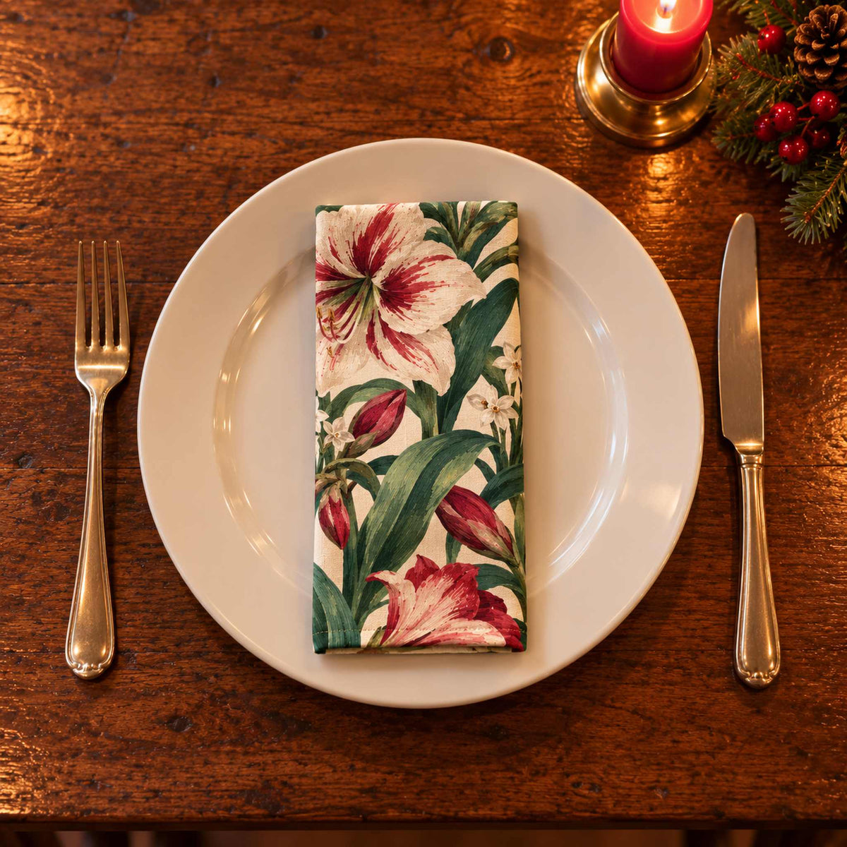 Ivory Amaryllis cotton napkin neatly folded on a dinner plate with cutlery and candlelight on a wooden Christmas table.