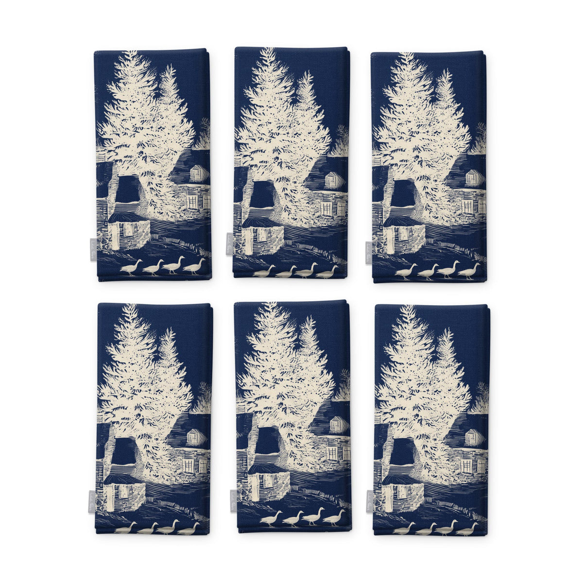 Village Toile Christmas napkins in ivory on navy, set of six, folded on white, showing the same fir tree and snowy cottage
