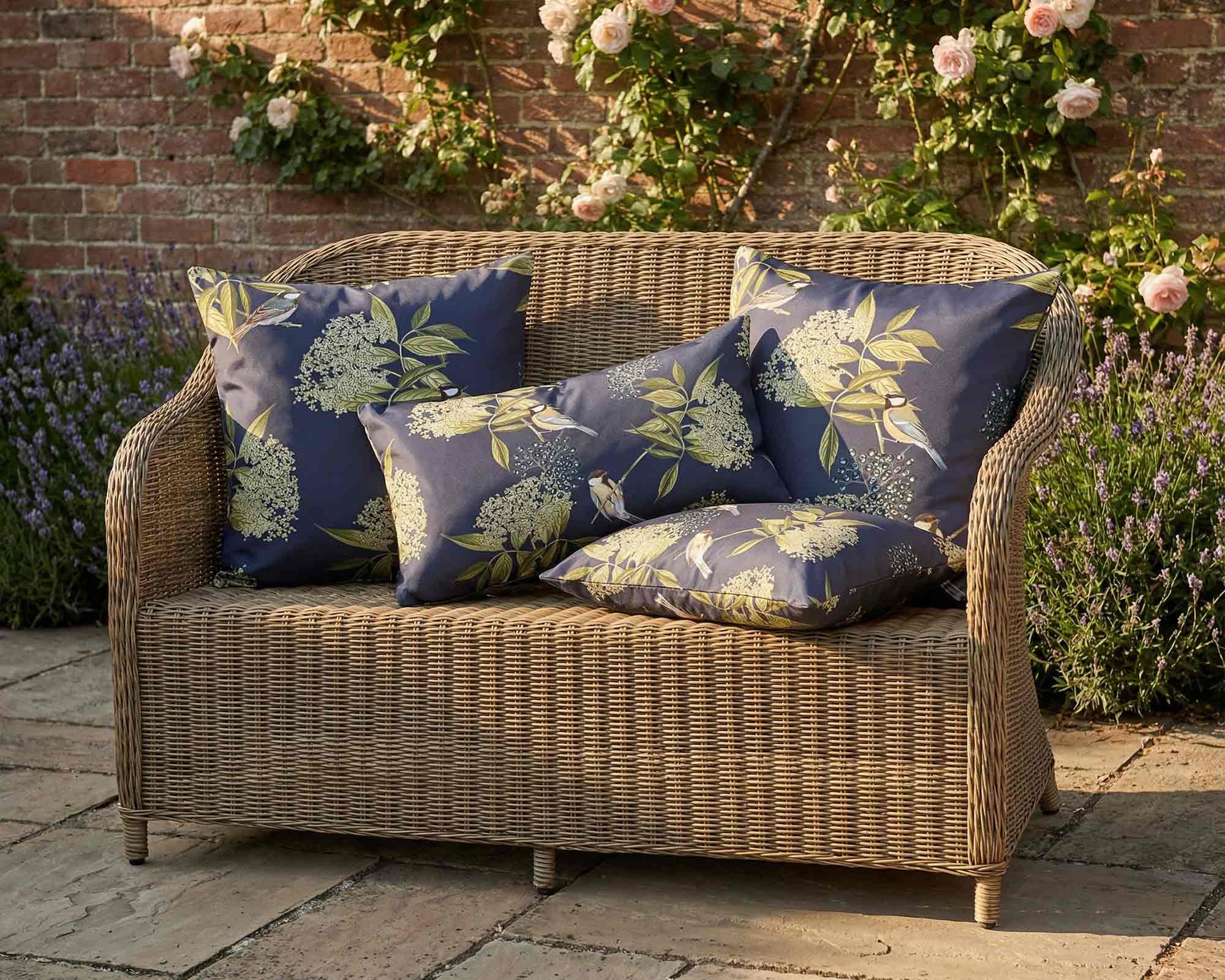 Navy floral bird print outdoor garden cushions on rattan style sofa