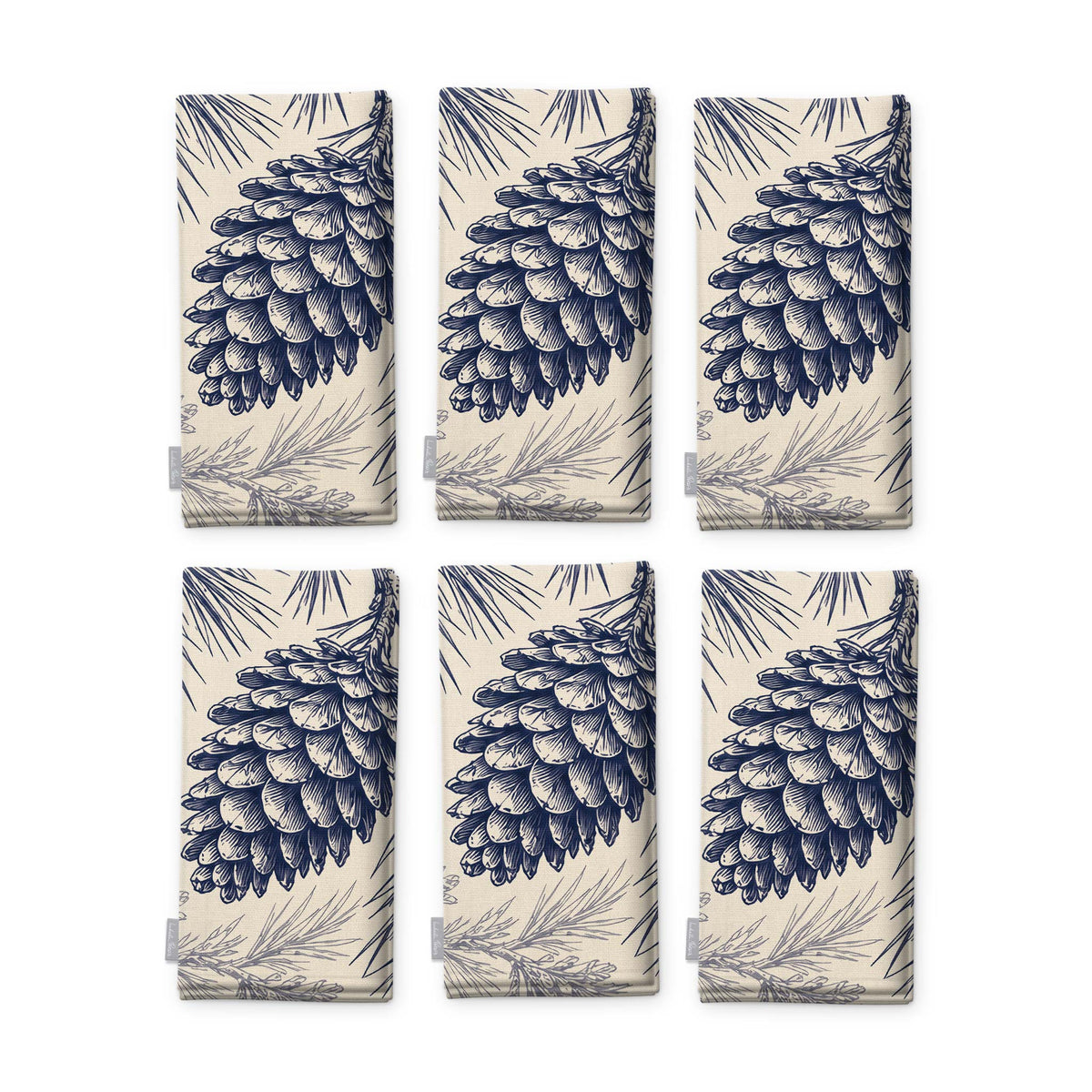 Pine Bough Christmas napkins in navy on ivory, set of six, folded on white, showing the same pine cone on a bough