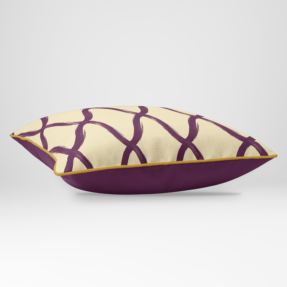 Angled view showing the front and Rich Plum plain reverse of a Palace Trellis rectangular cushion in Plum & Saffron, finished with Saffron piping.