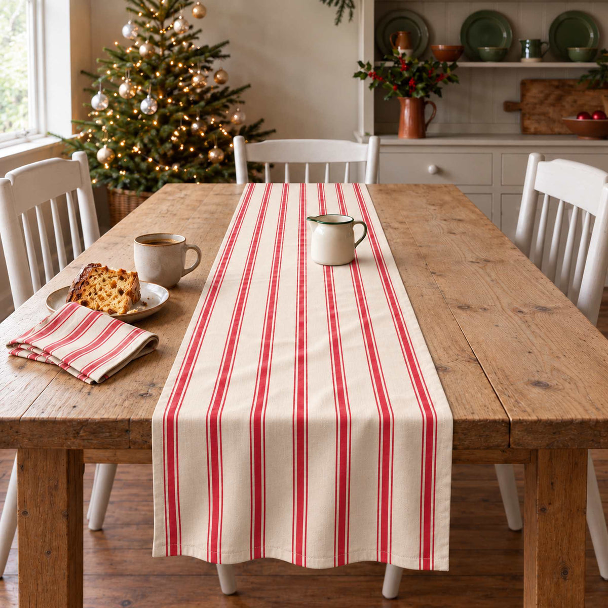 Ticking Stripe Christmas table runner in Red on ivory, styled on a wooden table with a softly draped end in a daylight Christmas room.