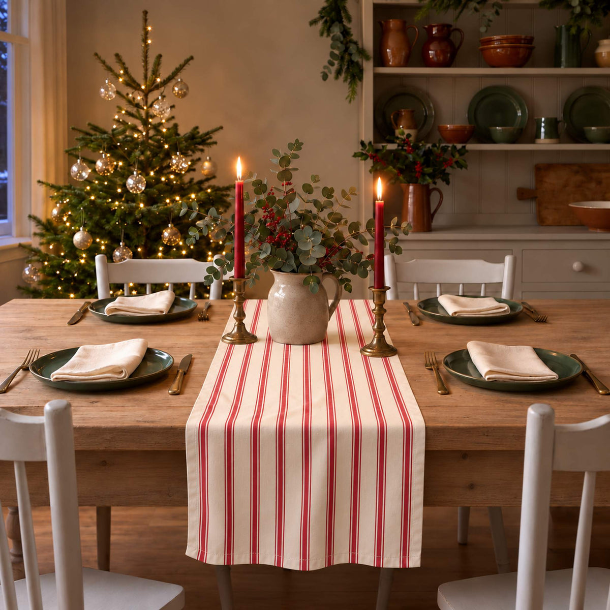 Ticking Stripe Christmas table runner in Red on ivory, styled on a wooden table with a softly draped end in a candlelit Christmas room.