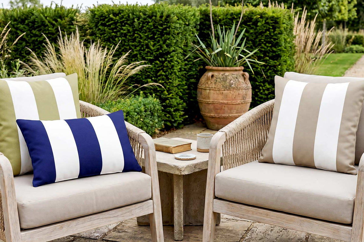 Sage, navy and taupe striped outdoor cushions on a pair of rope garden chairs in a British country garden.