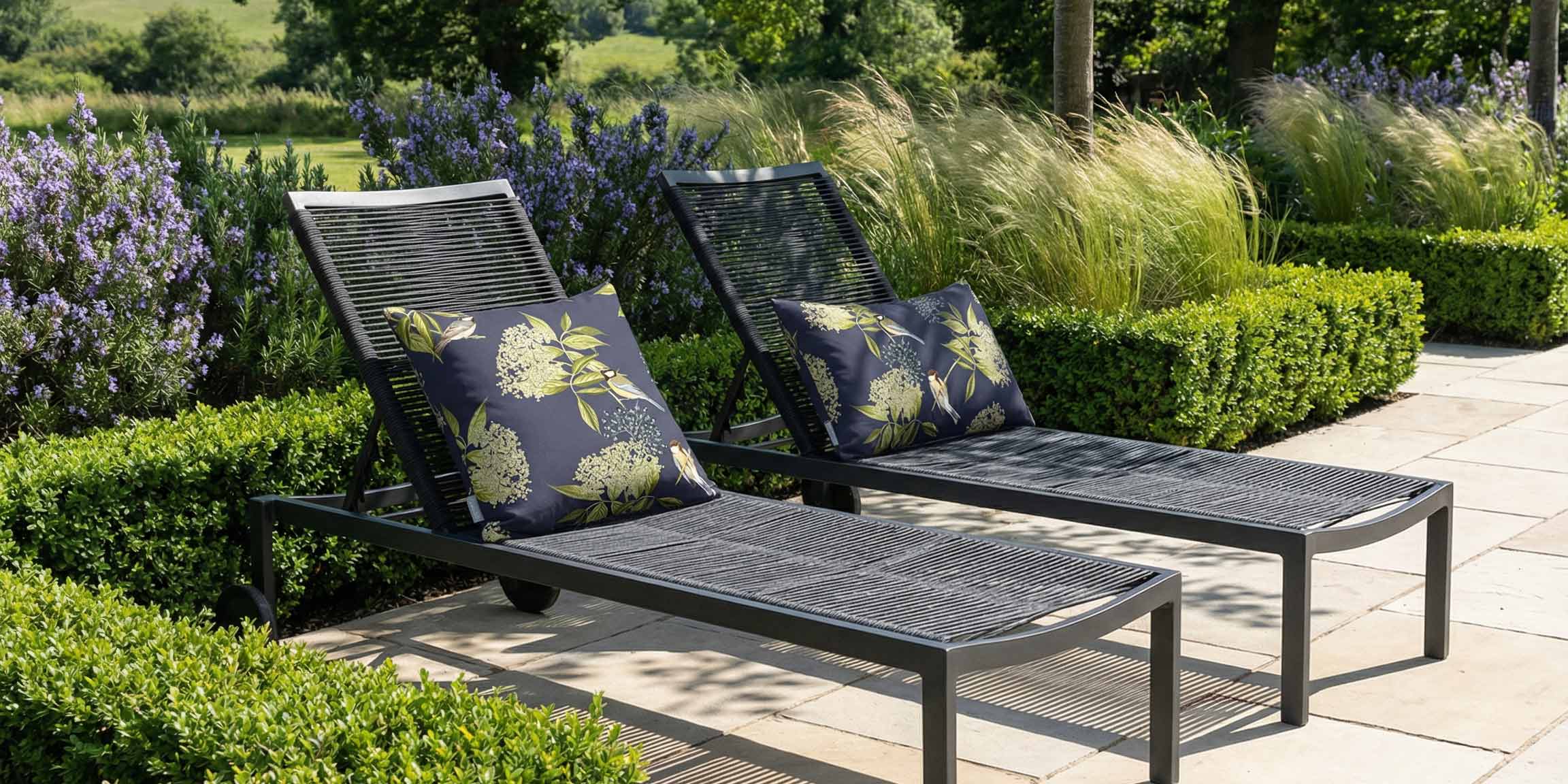 Outdoor garden loungers styled with Izabela Peters bird on elderflower waterproof cushions in a British garden setting