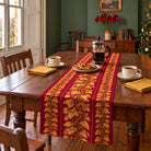 Gilded Ivy Christmas table runner in Burgundy and gold, styled on a wooden table with a softly draped end in a daylight Christmas room.