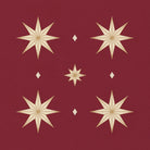 Close-up of the Stars Christmas napkin print in burgundy and gold on cotton, showing gold eight-pointed stars