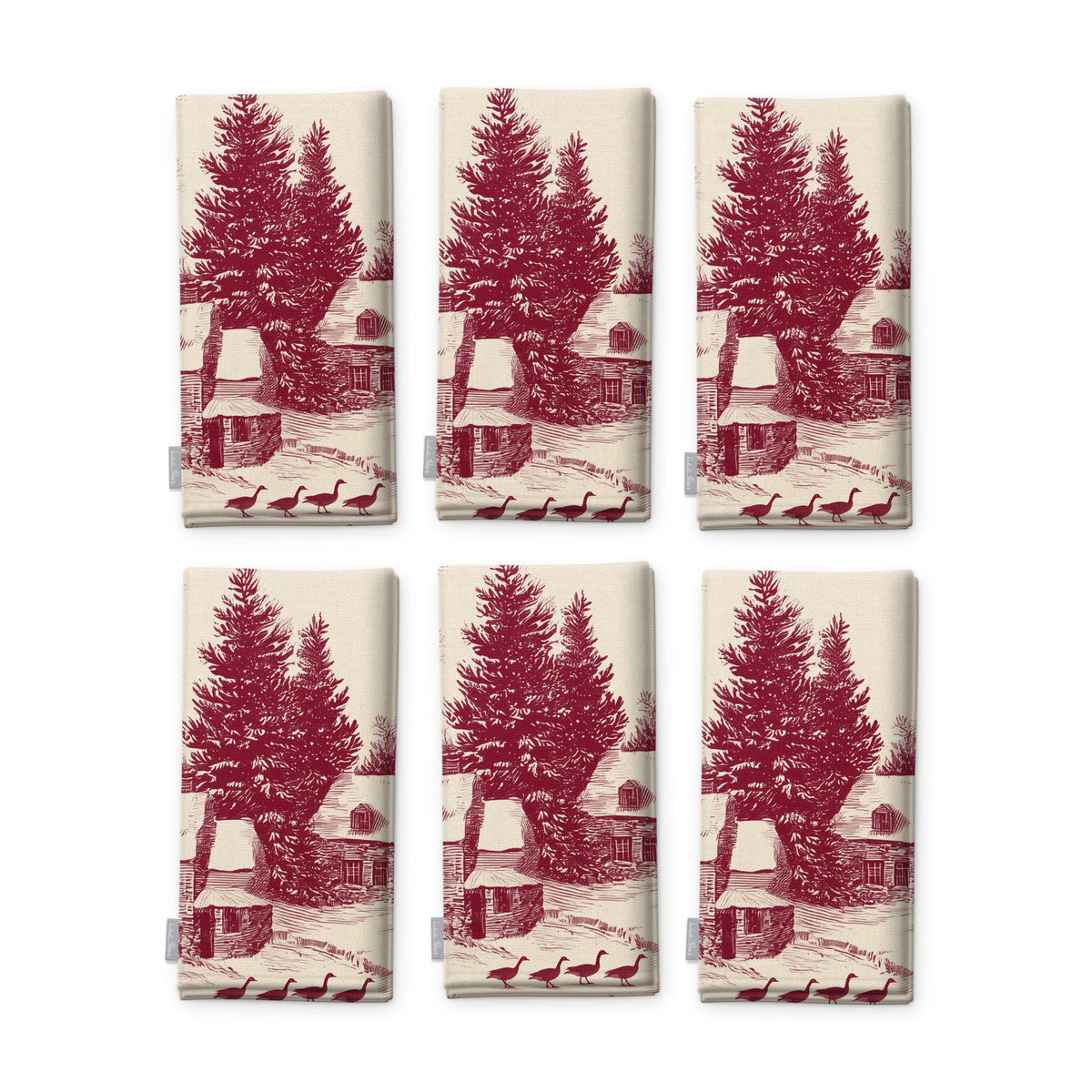 Village Toile napkins in burgundy on ivory, set of six, folded on white, showing the same fir tree and snowy cottage