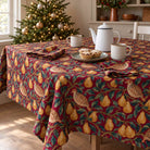 Burgundy Partridge and Pear Christmas tablecloth draped over a dining table with a white coffee pot, two mugs, mince pies and folded napkins in winter daylight.