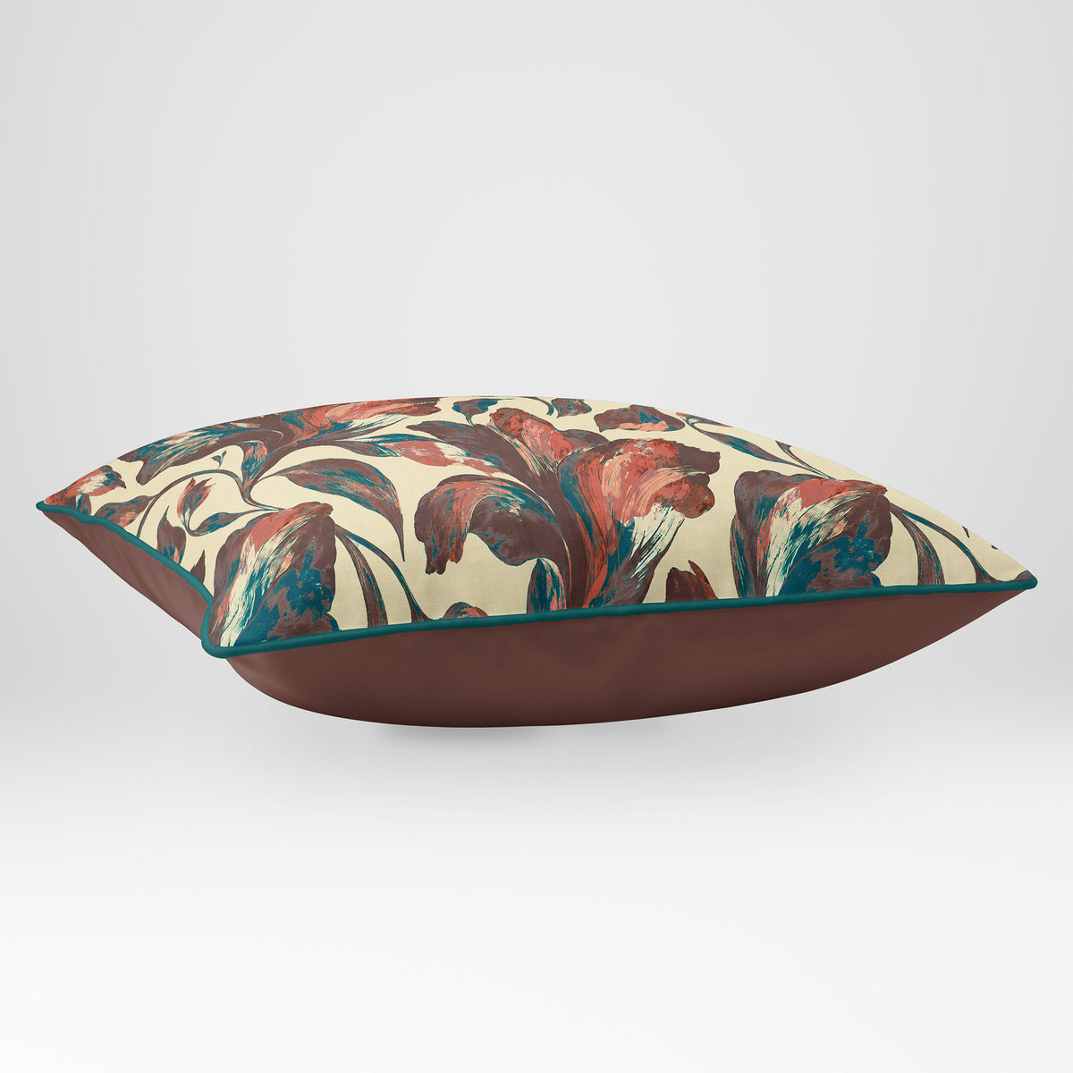 Angled view showing the front and Cocoa plain reverse of a Fiora Floral rectangular cushion in Cocoa & Teal, finished with Deep Teal piping.