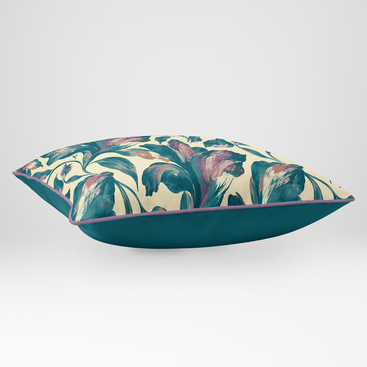 Angled view showing the front and Ink Blue plain reverse of a Fiora Floral rectangular cushion in Ink Blue & Lilac, finished with Muted Lilac piping.