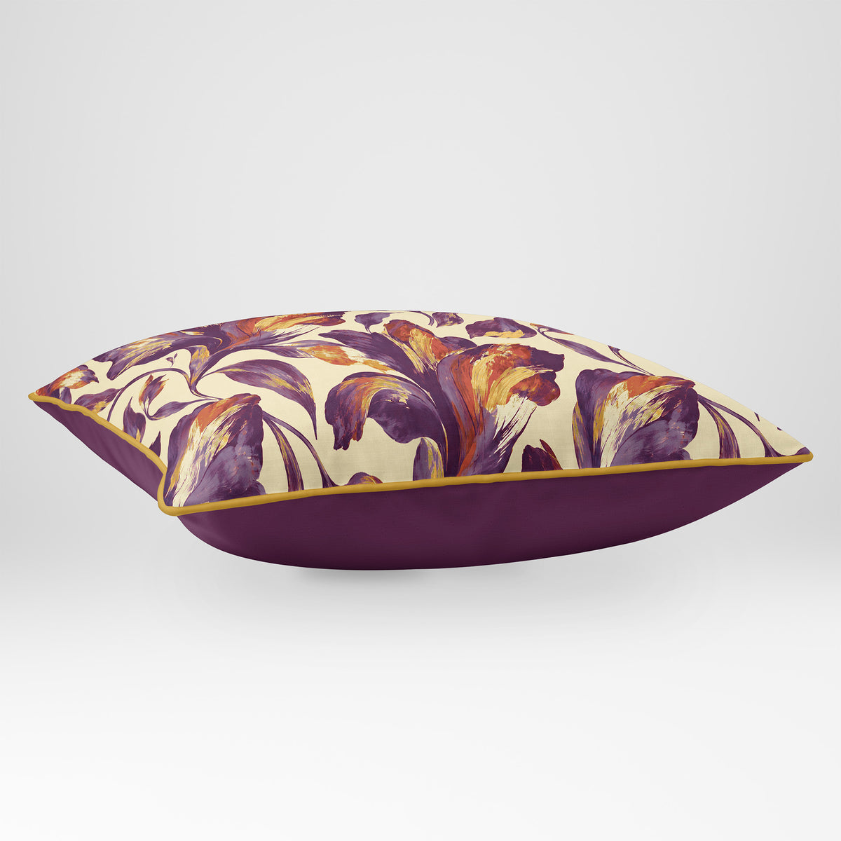 Angled view showing the front and Rich Plum plain reverse of a Fiora Floral rectangular cushion in Plum & Saffron, finished with Saffron piping.