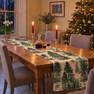 Fir Forest Toile Christmas table runner in Green on ivory, styled on a wooden table with a softly draped end in a candlelit Christmas room.