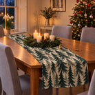 Spruce Stand Christmas table runner in Green on ivory, styled on a wooden table with a softly draped end in a candlelit Christmas room.