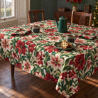 Ivory Amaryllis Christmas tablecloth draped over a dining table with a green coffee pot, mugs and matching floral napkins in soft winter daylight.
