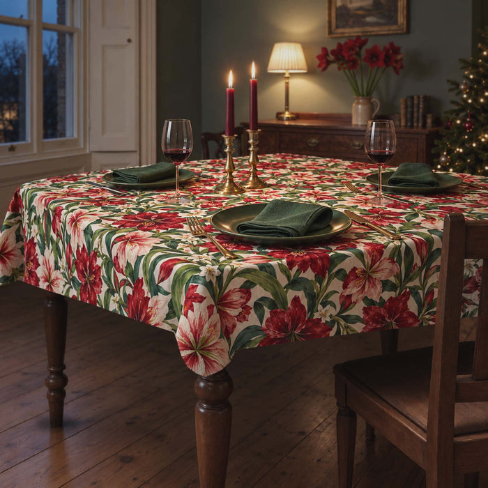 Ivory Amaryllis Christmas tablecloth on a rectangular dining table set for dinner, with two glasses of red wine, red candles and green plates in a green Victorian dining room.