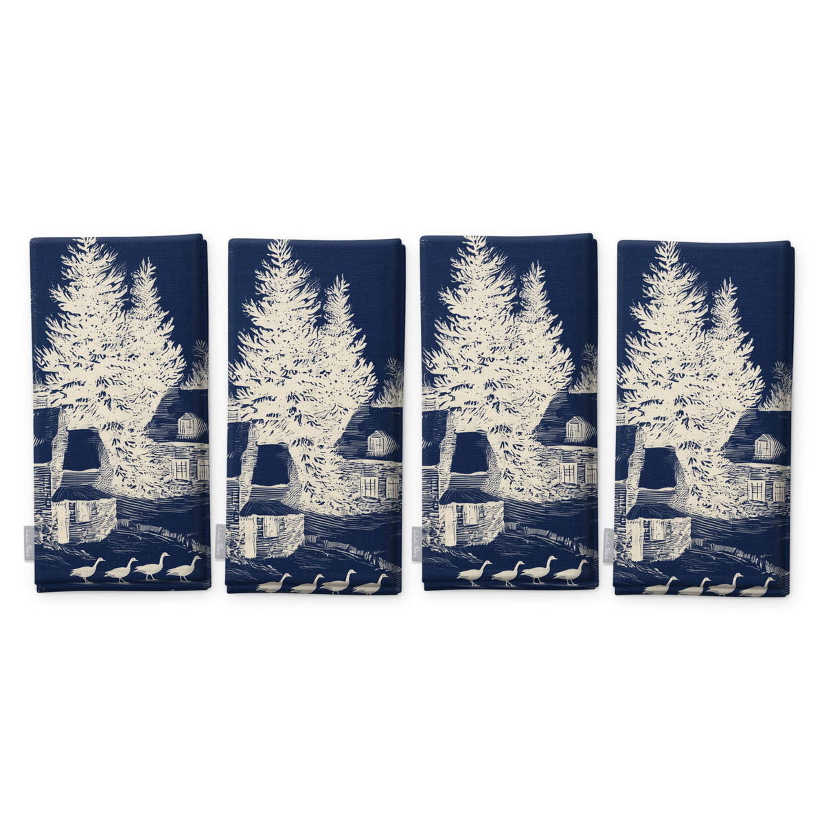 Village Toile Christmas napkins in ivory on navy, set of four, folded on white, showing the same fir tree and snowy cottage