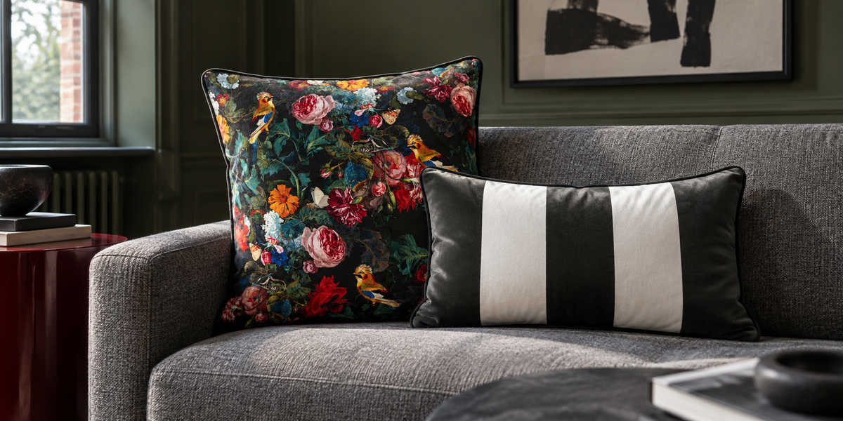 Charcoal Birds in Paradise square and striped rectangular velvet cushions on a pewter sofa against olive walls.