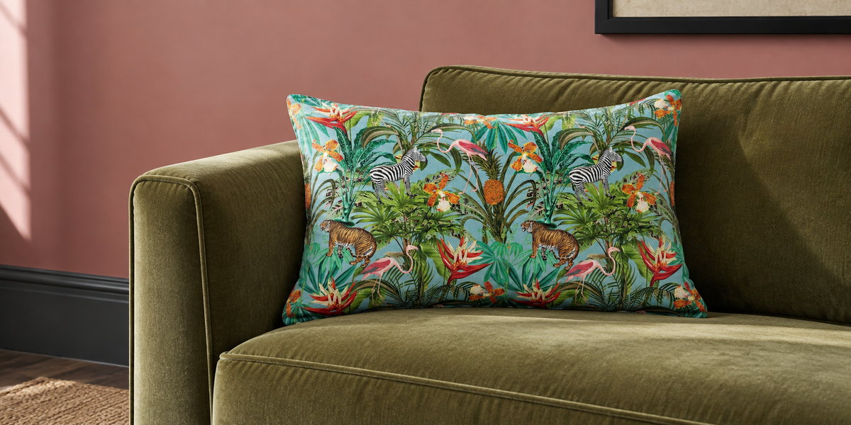 Blue Surf Jungle Fusion rectangular velvet cushion on an olive sofa against a muted pink wall.