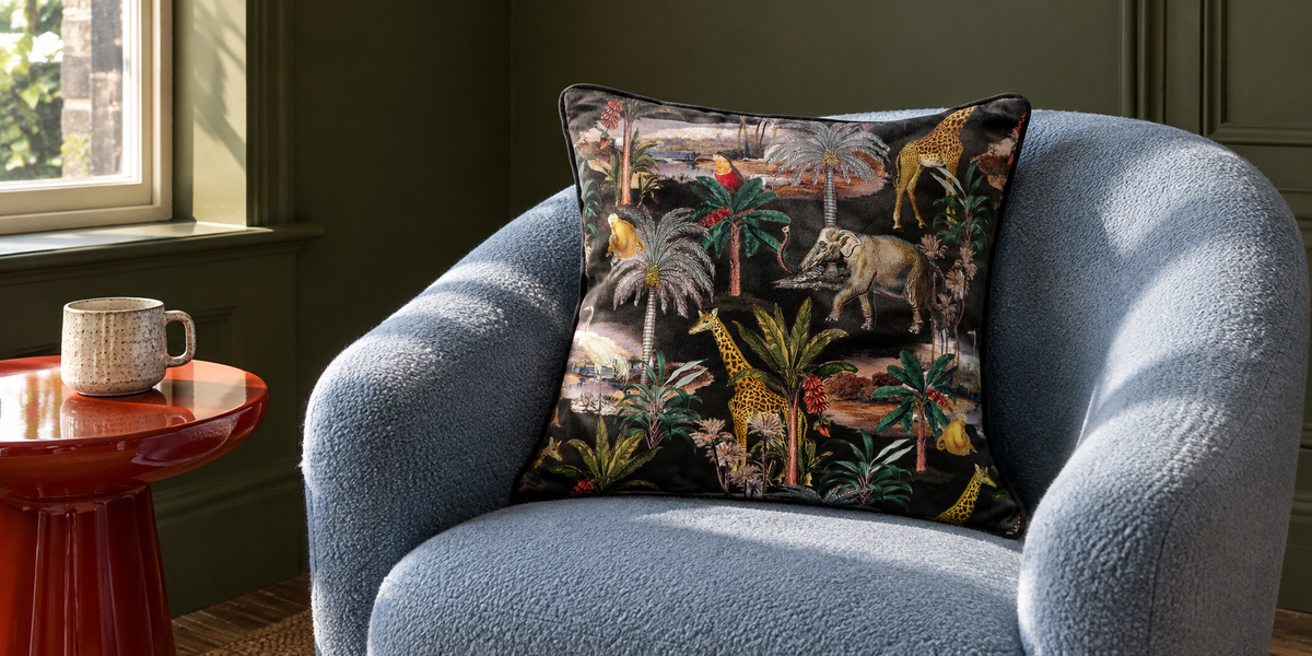 Charcoal Safari Voyage velvet cushion on a powder blue chair against an olive wall.