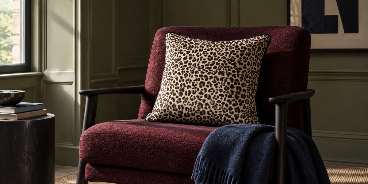 Cream Leopard Print velvet cushion on an oxblood chair in a lichen green room.