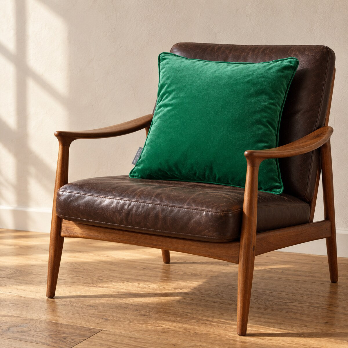 Emerald Green piped velvet cushion on a dark leather and teak chair.