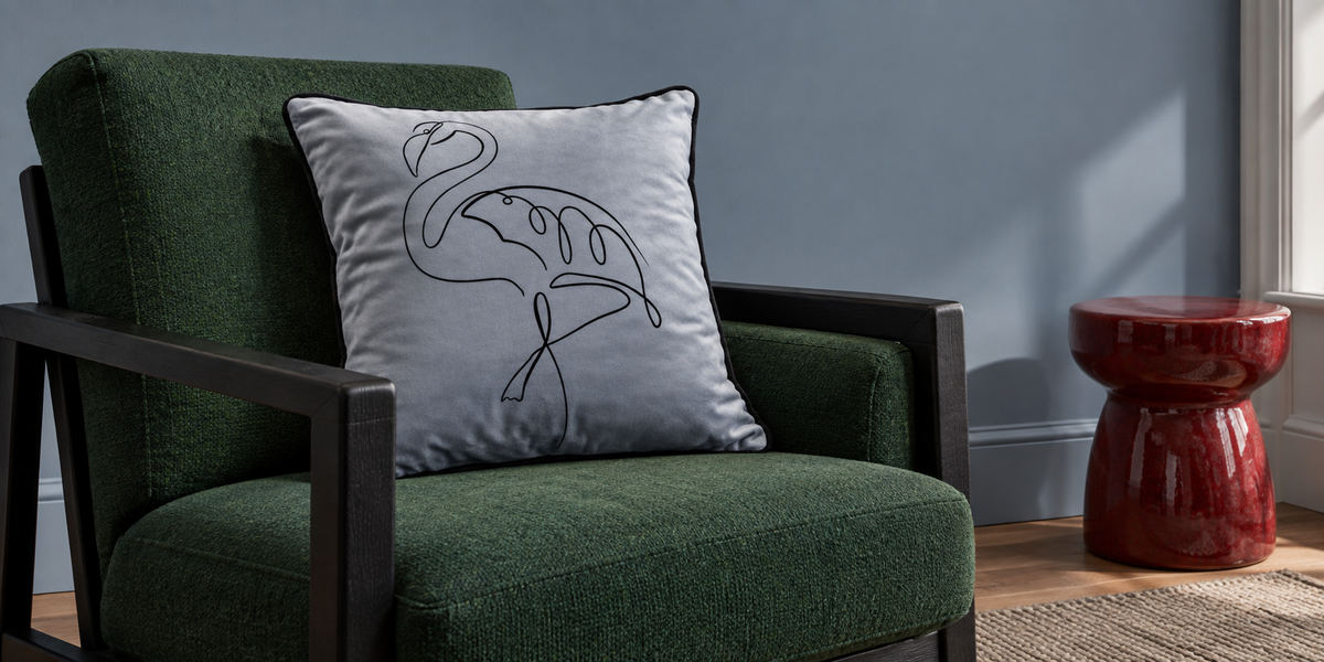French Grey Abstract Flamingo velvet cushion on a green chair in a blue painted room.