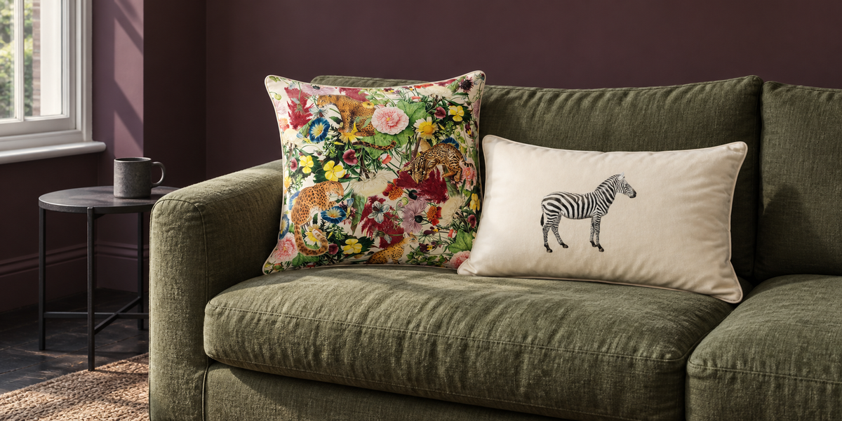 Ivory Cream Junglescape and Zebra velvet cushions on an olive sofa against plum walls.
