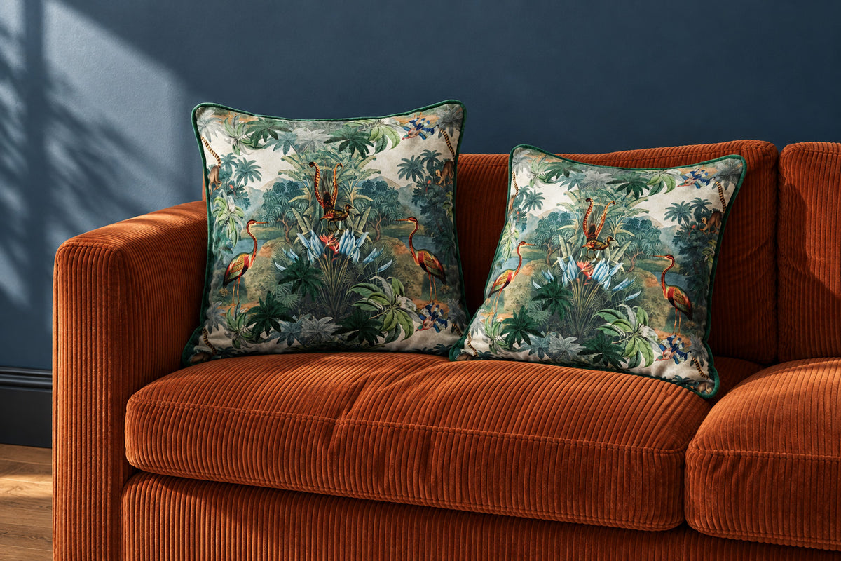 Two Kilimanjaro velvet cushions on a rust-orange corduroy sofa against a smoky blue painted wall.