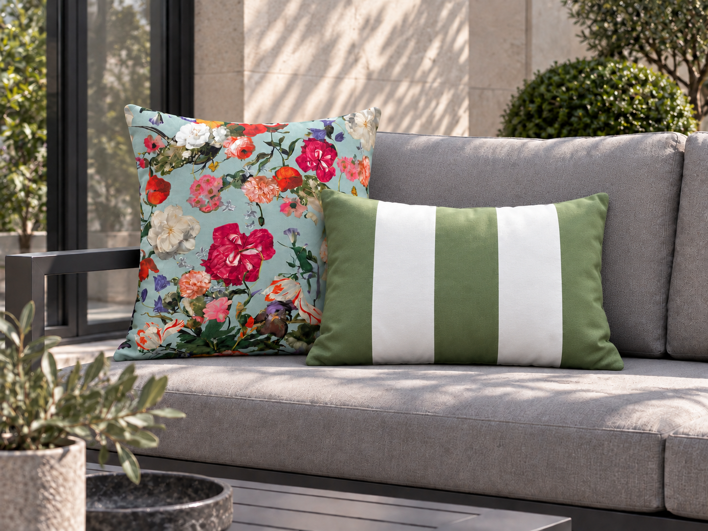 Large Blue Surf floral square and sage striped rectangular cushions on the same grey garden sofa.