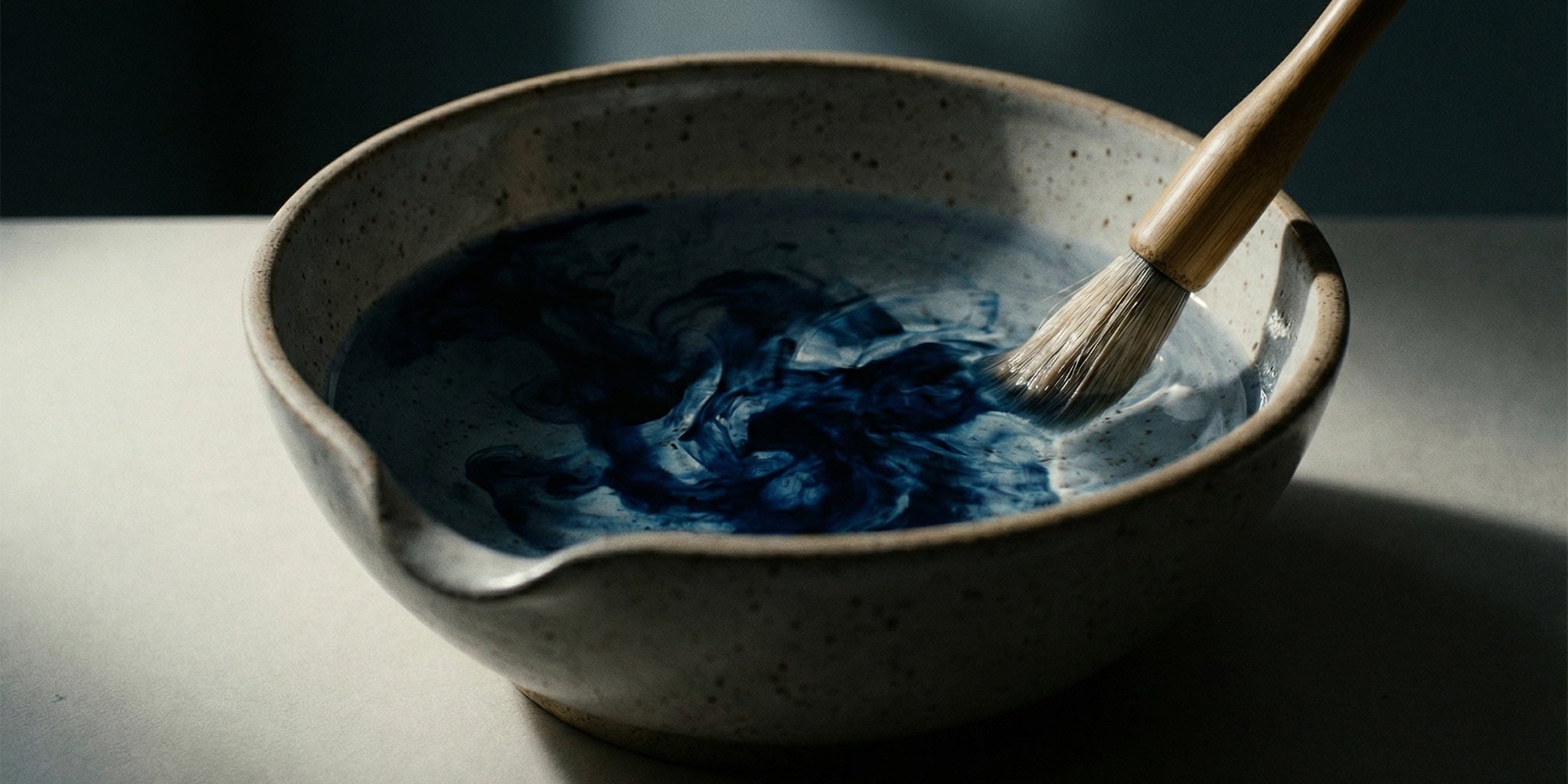 Blue pigment and a brush in a ceramic bowl.