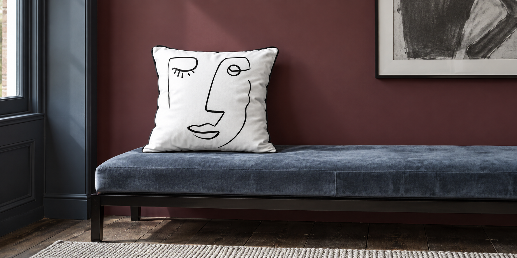 White and Black Open Face velvet cushion on a smoky blue bench against a burgundy wall.