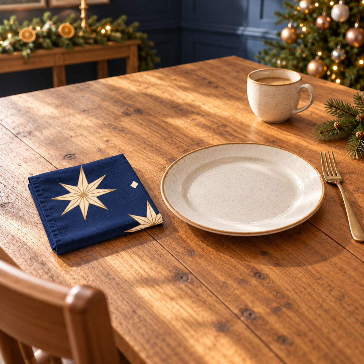 Navy and gold Stars cotton napkin in a compact square fold beside a dinner plate and coffee cup on a wooden table in daylight.