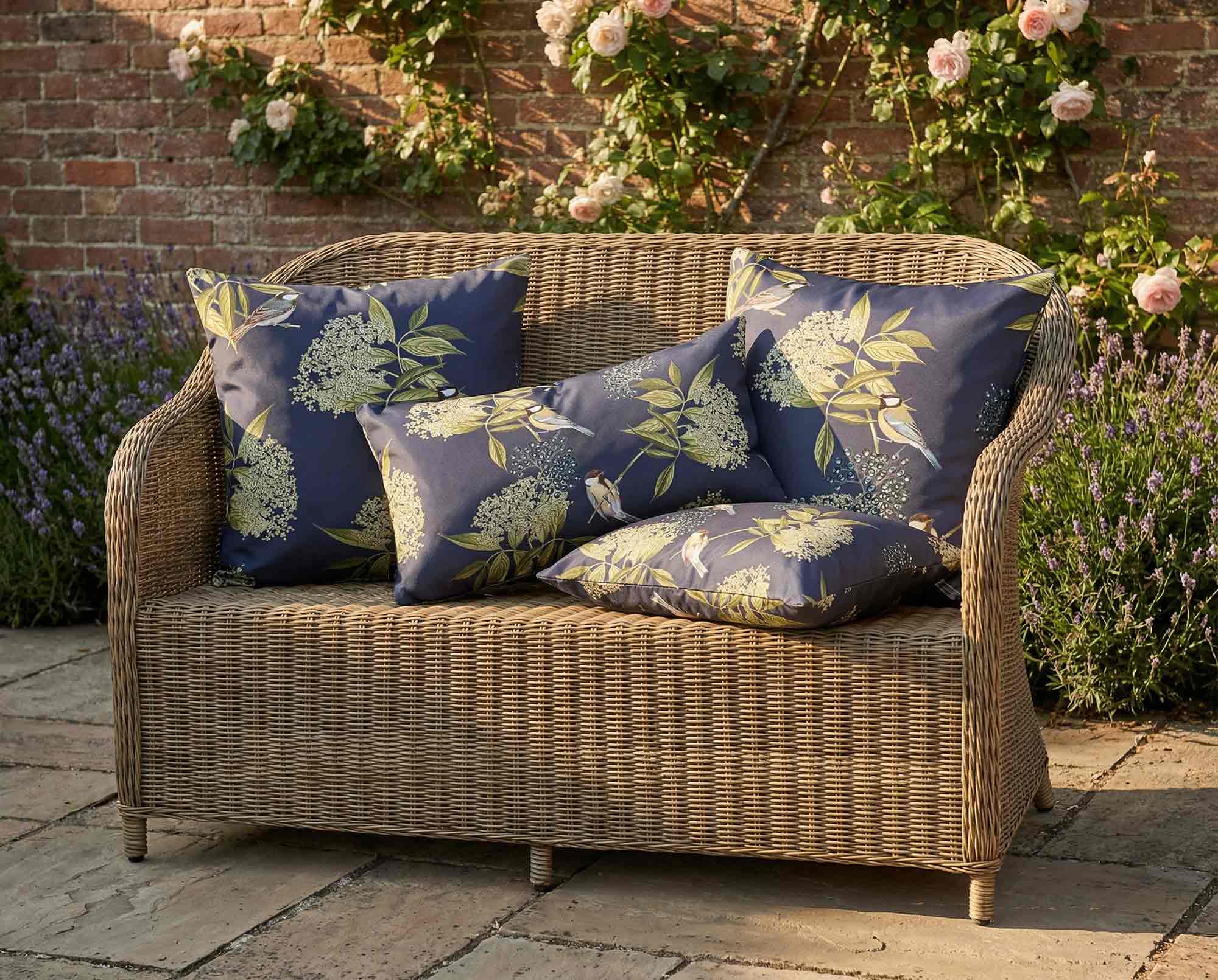Navy floral bird print outdoor garden cushions on rattan style sofa