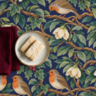 Navy Robins and Christmas Roses tablecloth with shortbread on a stoneware plate and a folded burgundy napkin