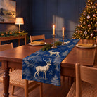 Stag Woodland Christmas table runner in Navy, styled on a wooden table with a softly draped end in a candlelit Christmas room.