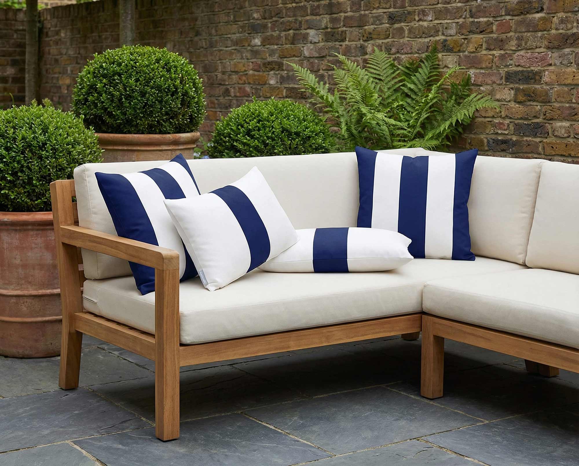 Midnight blue striped outdoor garden cushions styled on a wooden sofa in a modern UK garden