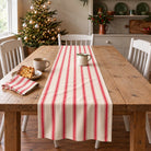 Ticking Stripe Christmas table runner in Red on ivory, styled on a wooden table with a softly draped end in a daylight Christmas room.