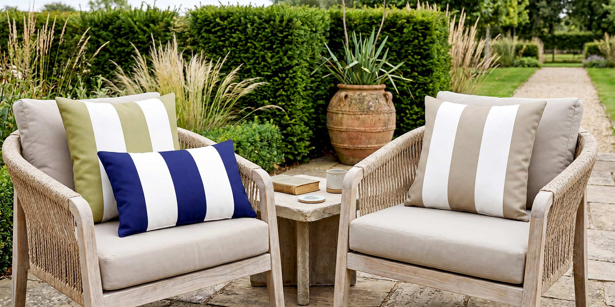 Sage, navy and taupe striped outdoor cushions on a pair of rope garden chairs in a British country garden.